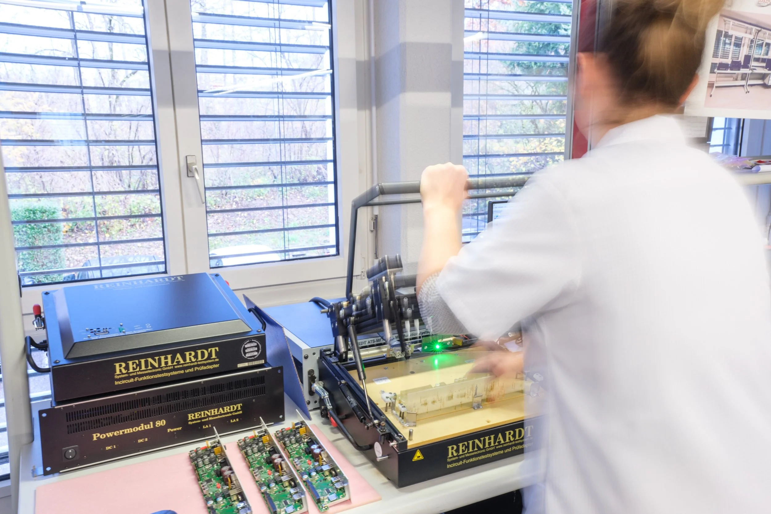 Forscherin arbeitet mit elektronischen Testgeräten in einem Laborraum mit Fenster