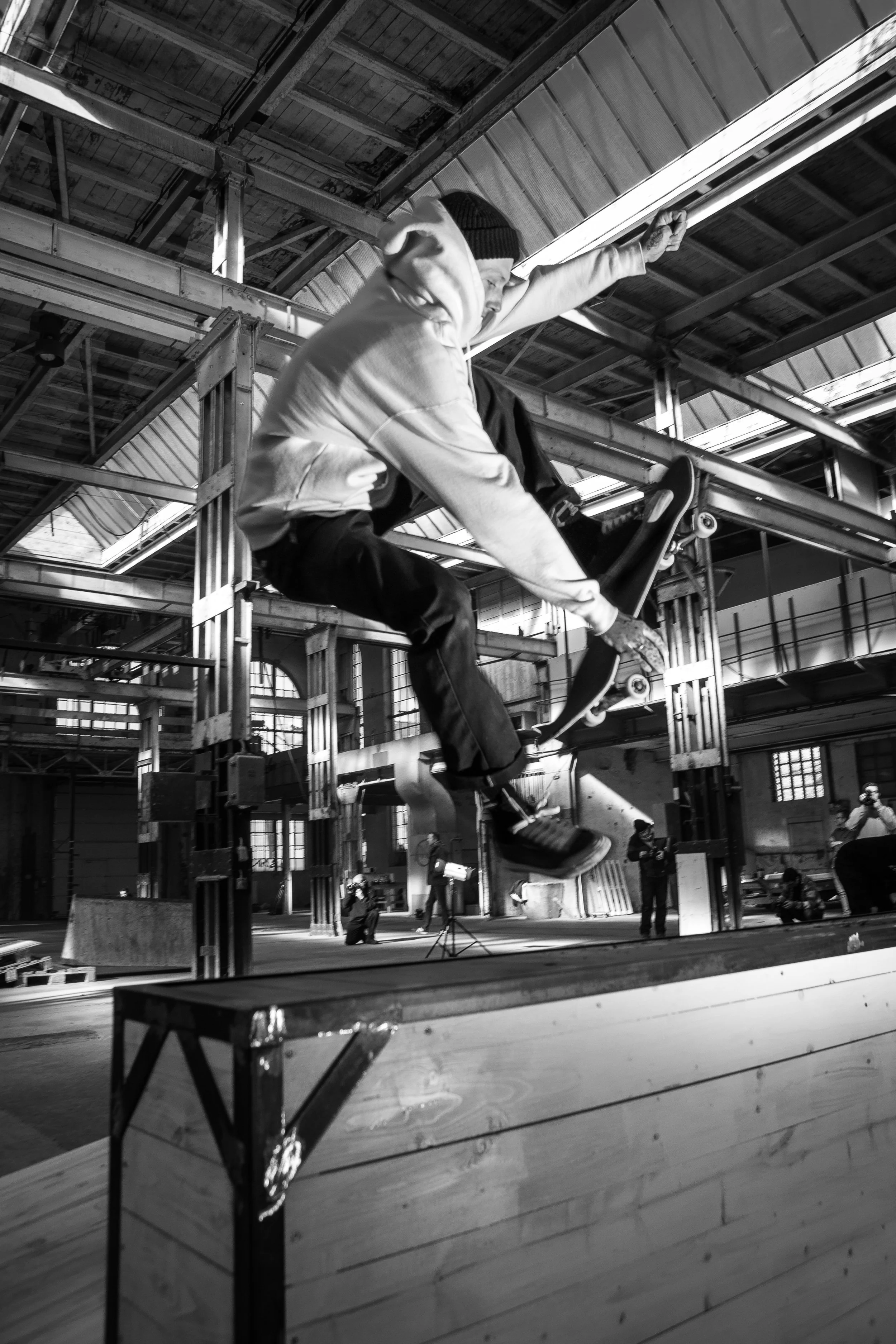 Ein Skater macht einen Trick in einer indoor Skatehalle, schwarz-weiß, Actionaufnahme.