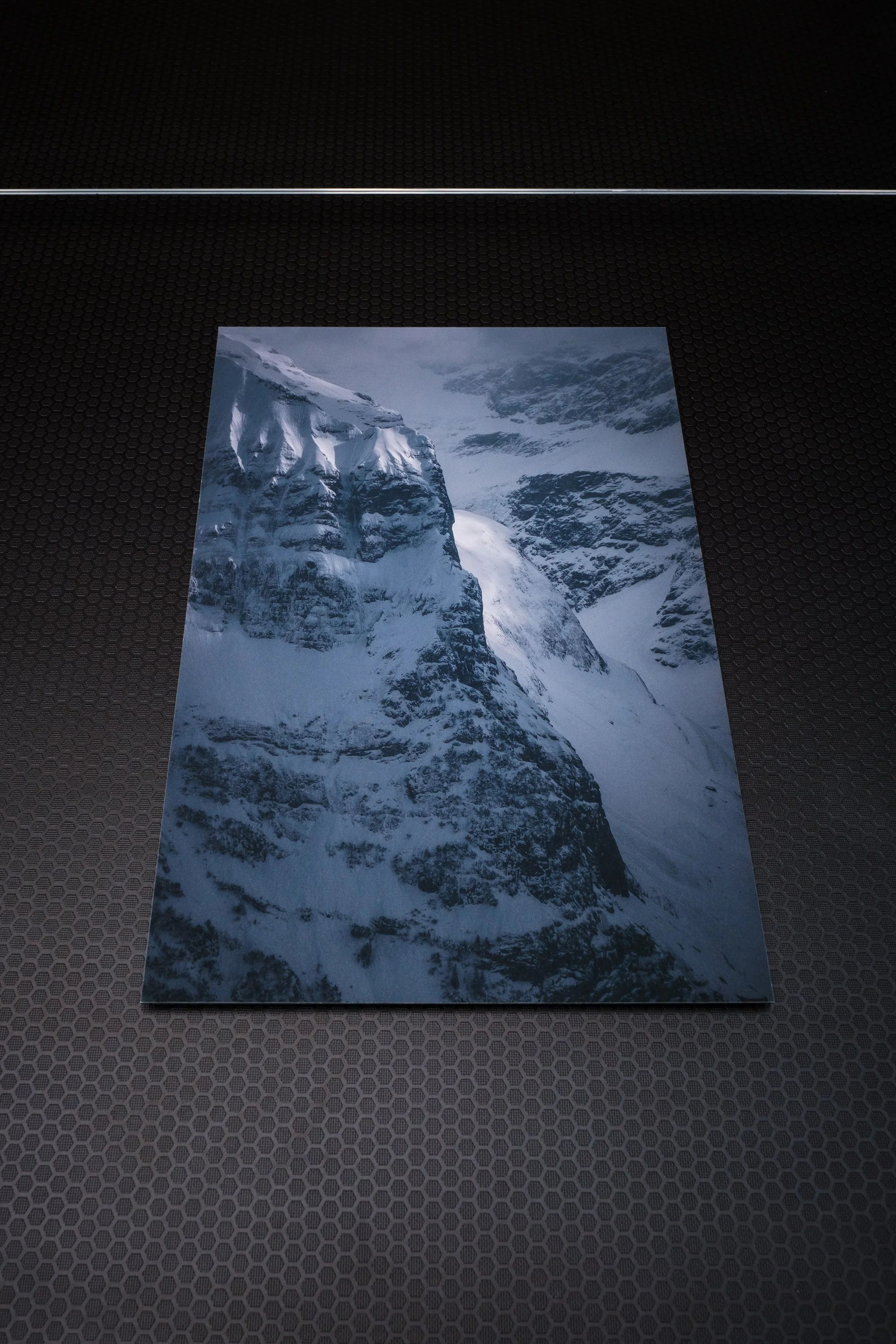 Fotografie einer verschneiten Berglandschaft mit steilen Felswänden und Gletschern.